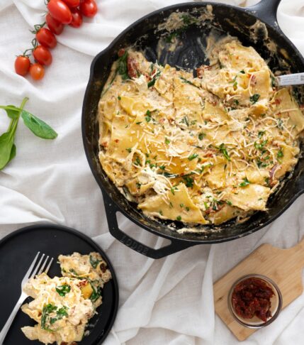 A vegan skillet lasagna in a cast iron pan surrounded by various ingredients