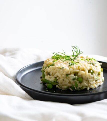 a plate of spring risotto with asparagus. peas. arugula, and fennel